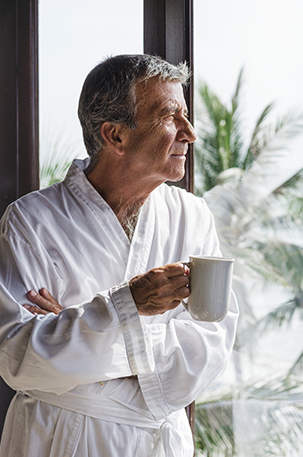 Man at hotel room window with a cup of coffee