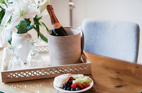 Champaign bottle in bucket with glasses in a bamboo tray on a wooden table