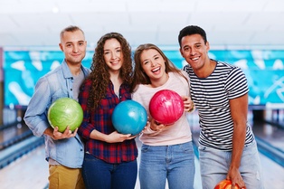 4 people posing for picture with bowling balls