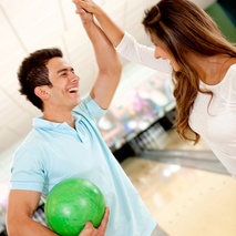 man and woman doing high five while bowling